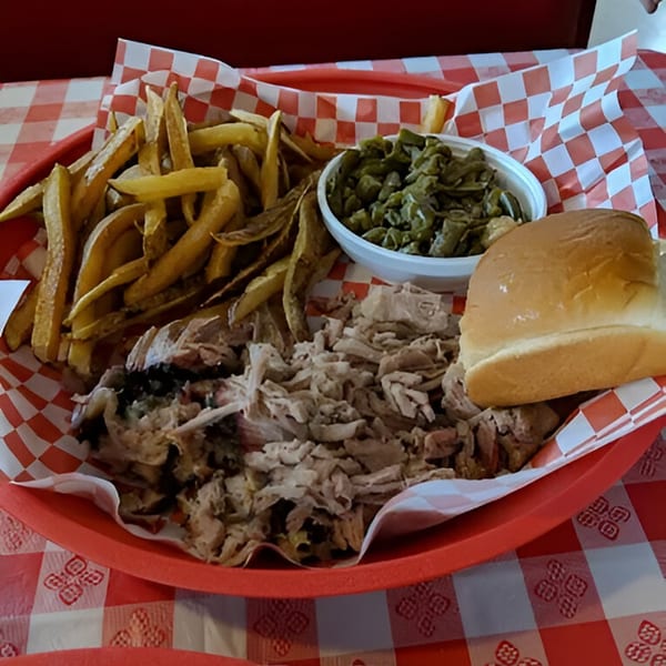 A Fire It Up BBQ pulled pork platter with fries, green beans, and a bun on a red tray.