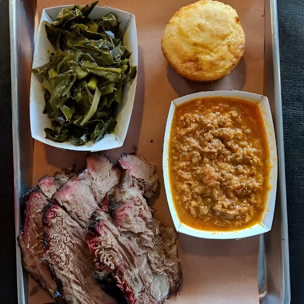 Fire It Up BBQ brisket plate with collard greens, baked beans, and cornbread on a tray.