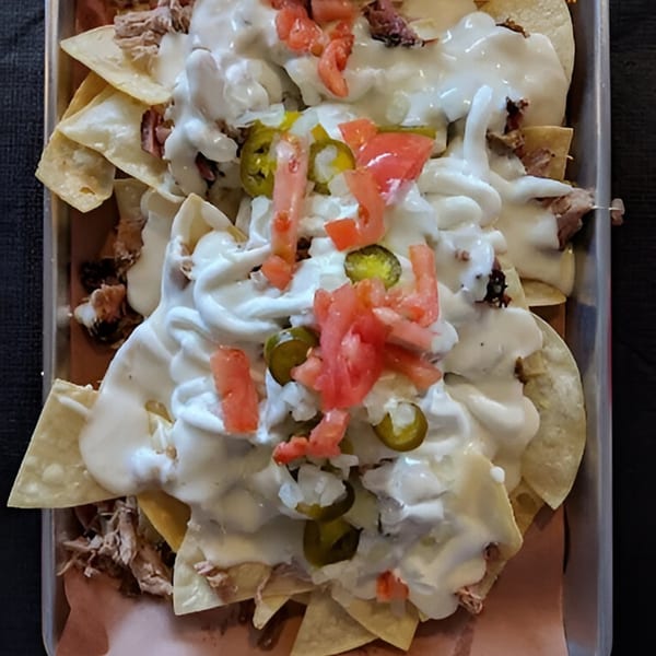 Fire It Up BBQ nachos with pulled pork, white cheese sauce, jalapeños, and diced tomatoes.