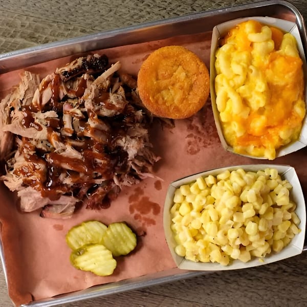 Fire It Up BBQ tray with pulled pork, cornbread, mac and cheese, creamed corn, and pickles.